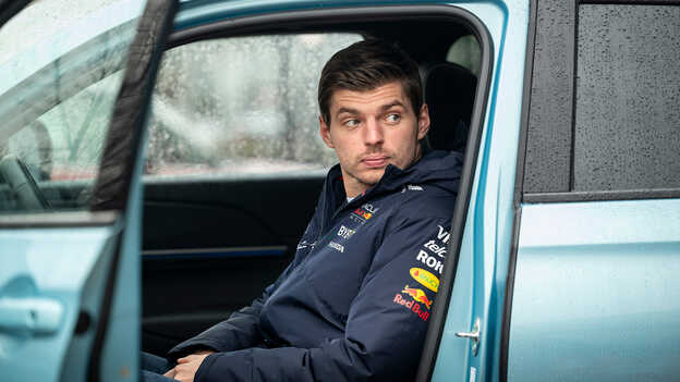 Max Verstappen in einem geparkten e:Ny1 in Blau.