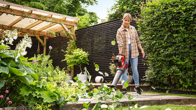 Frau mit Akku-Laubbläser in einem Garten