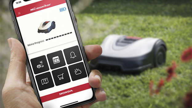 Mii-Monitor-App auf einem Smartphone und ein Miimo im Hintergrund auf dem Rasen.
