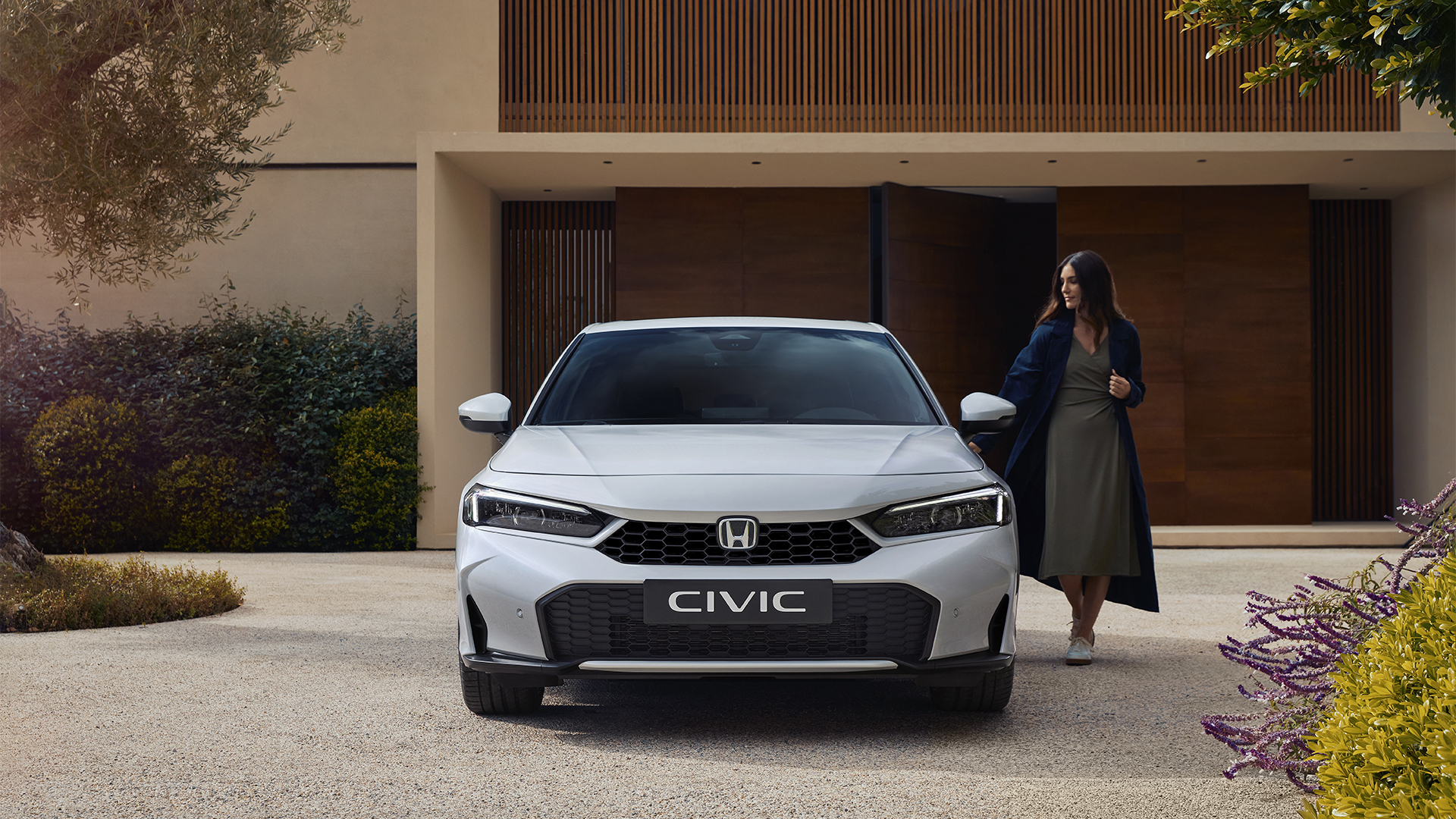 Frontalaufnahme eines Civic Hybrid, dessen Tür von einer Frau geöffnet wird.