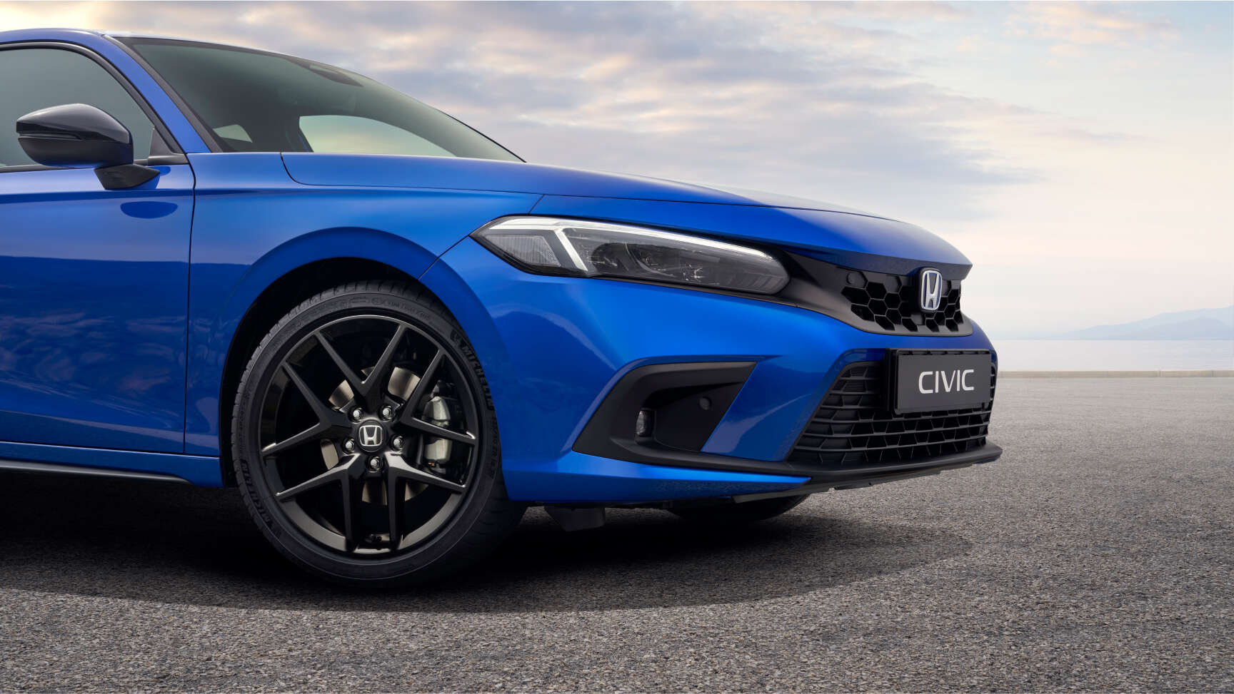 Nahaufnahme des Honda Civic e:HEV mit Aussenspiegeln und Leichtmetallfelgen in glänzendem Schwarz.