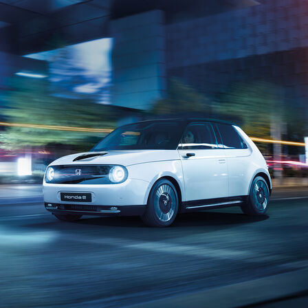 Honda e, 3/4-Frontansicht, in der Stadt fahrend.