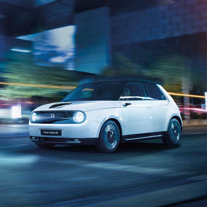 Honda e, 3/4-Frontansicht, in der Stadt fahrend.