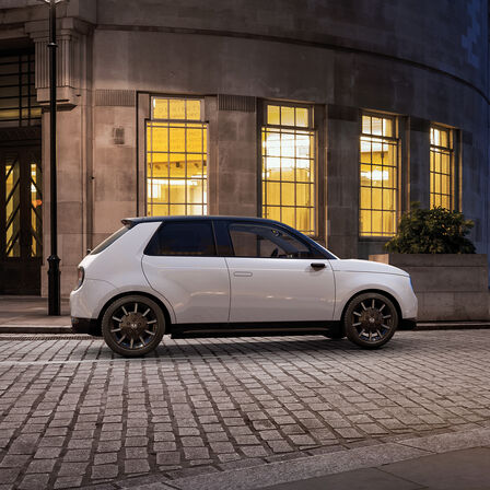 Honda e, Seitenansicht, vor Gebäuden in der Stadt geparkt. 