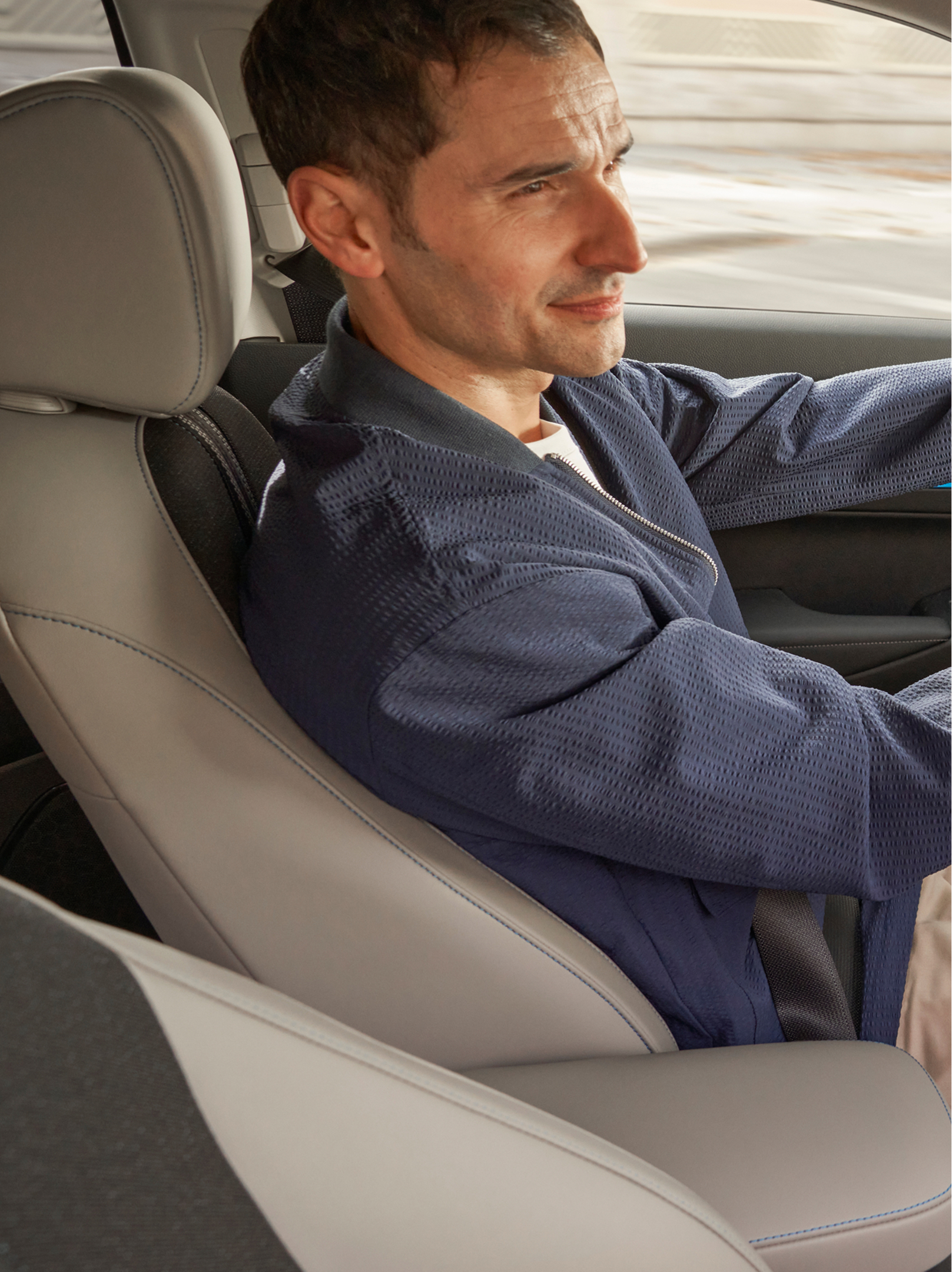 Ein Fahrer sitzt am Steuer eines Honda HR-V; von der Beifahrerseite aus gesehen, das Innenraum-Armaturenbrett ist zu sehen und eine Navigationskarte auf dem mittleren Bildschirm.