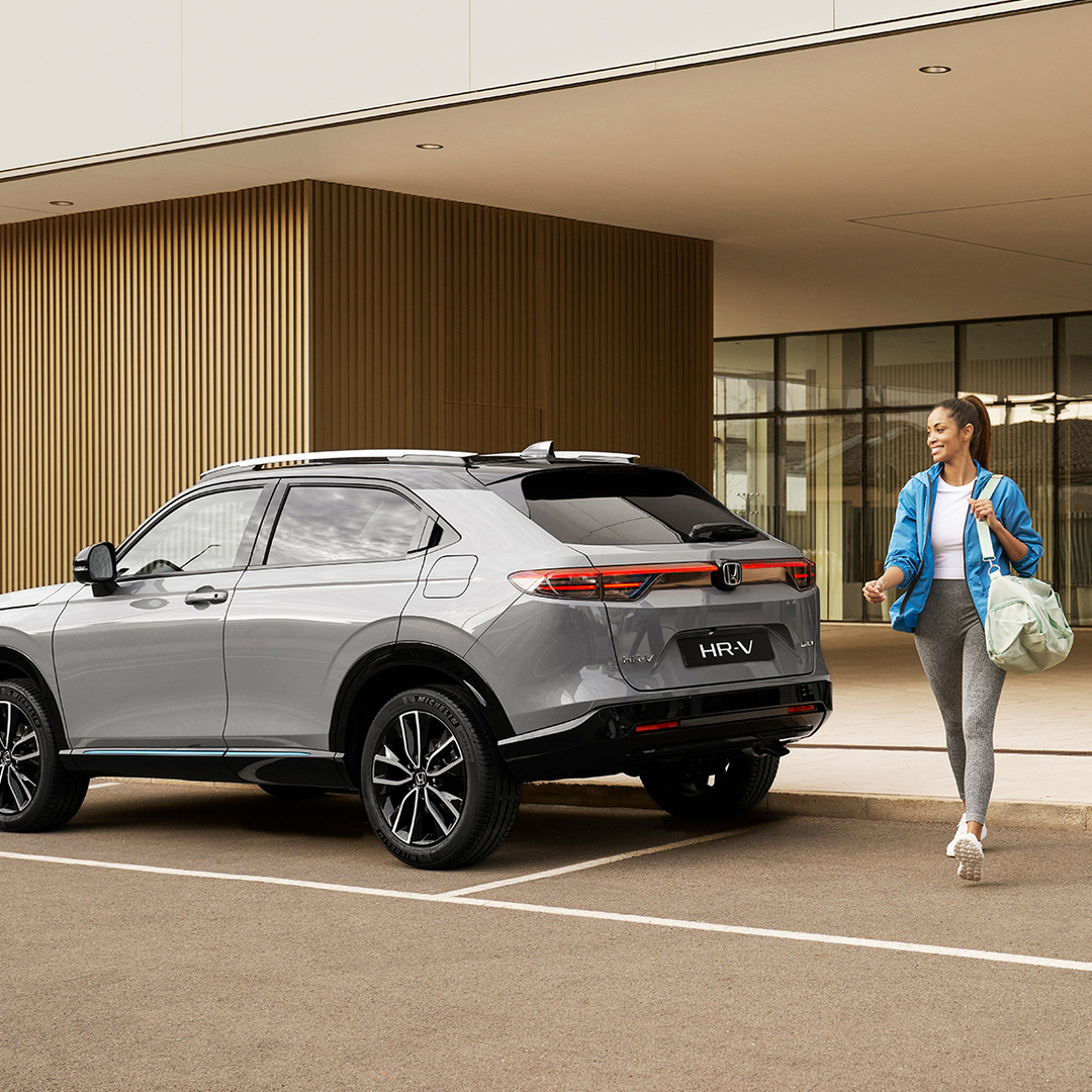 Eine Frau läuft neben einem geparkten HR-V.