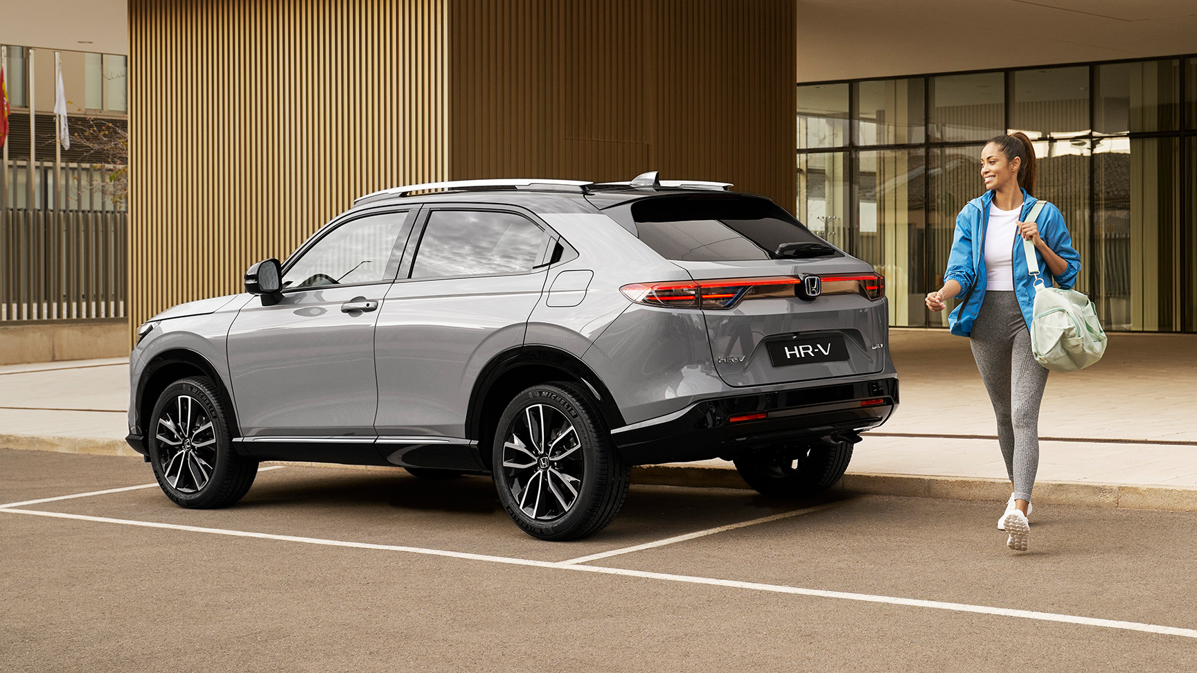 Frau geht an einem geparkten HR-V vorbei. 