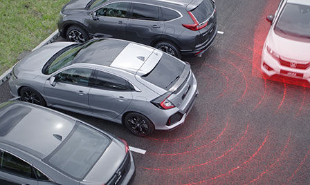 Honda Sensing Auto in einem Parkhaus mit Darstellung der Funktioalität des Ausparkassistents CTM und des Toter-Winkel-Assistenten.