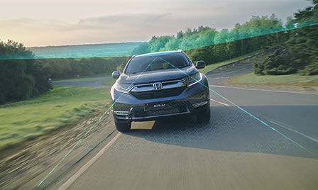 Honda Sensing Auto in ländlicher Umgebung mit Darstellung der Abfahrt-Minderung und Verkehrszeichenerkennung.