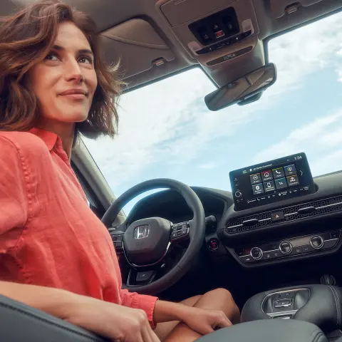 Honda ZR-V Hybrid, Frau auf dem Fahrersitz, die den Infotainment-Bildschirm verwendet.
