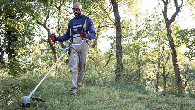 Close up of model trimming a field with Honda cordless brushcutter.