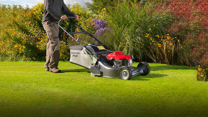 Mann mit Honda HRH Rasenmäher beim Mähen in einem Garten