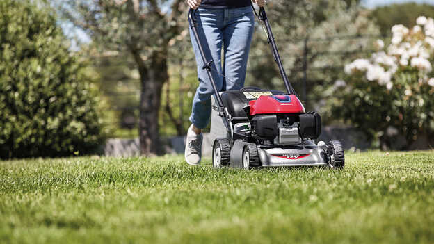 Seitenansicht: Frau mit Honda IZY Rasenmäher in einem Garten