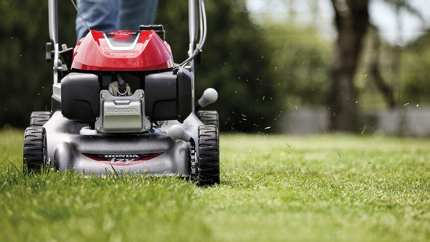 Seitenansicht: Frau mit Honda IZY Rasenmäher in einem Garten