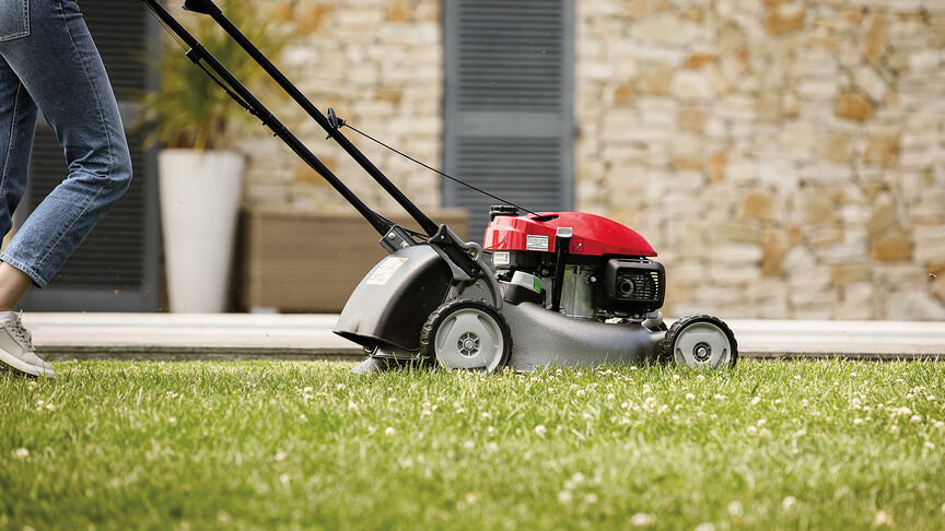 Seitenansicht: Frau mit Honda IZY Rasenmäher in einem Garten