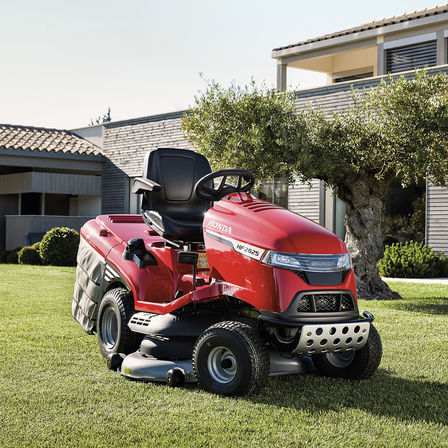 3/4-Vorderansicht eines Honda Traktors in einem Garten mit Haus im Hintergrund