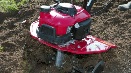 Nahaufnahme einer Mini-Motorhacke, Gartenumgebung.