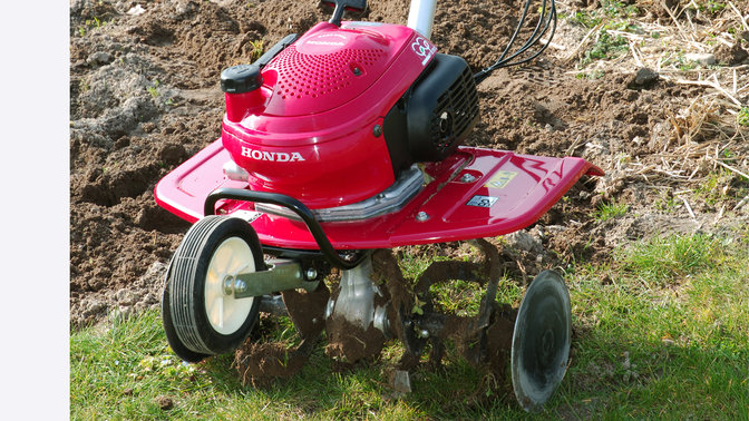 Nahaufnahme einer Mini-Motorhacke, Gartenumgebung.