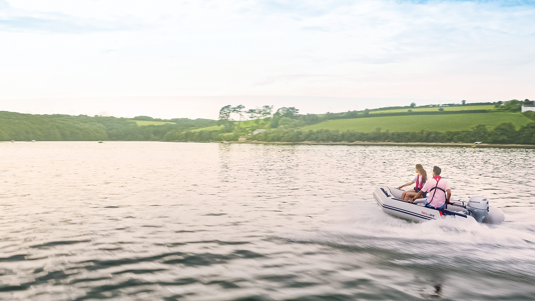 Paar auf einem Honwave-Boot mit Honda BF-Motor auf einem See. 