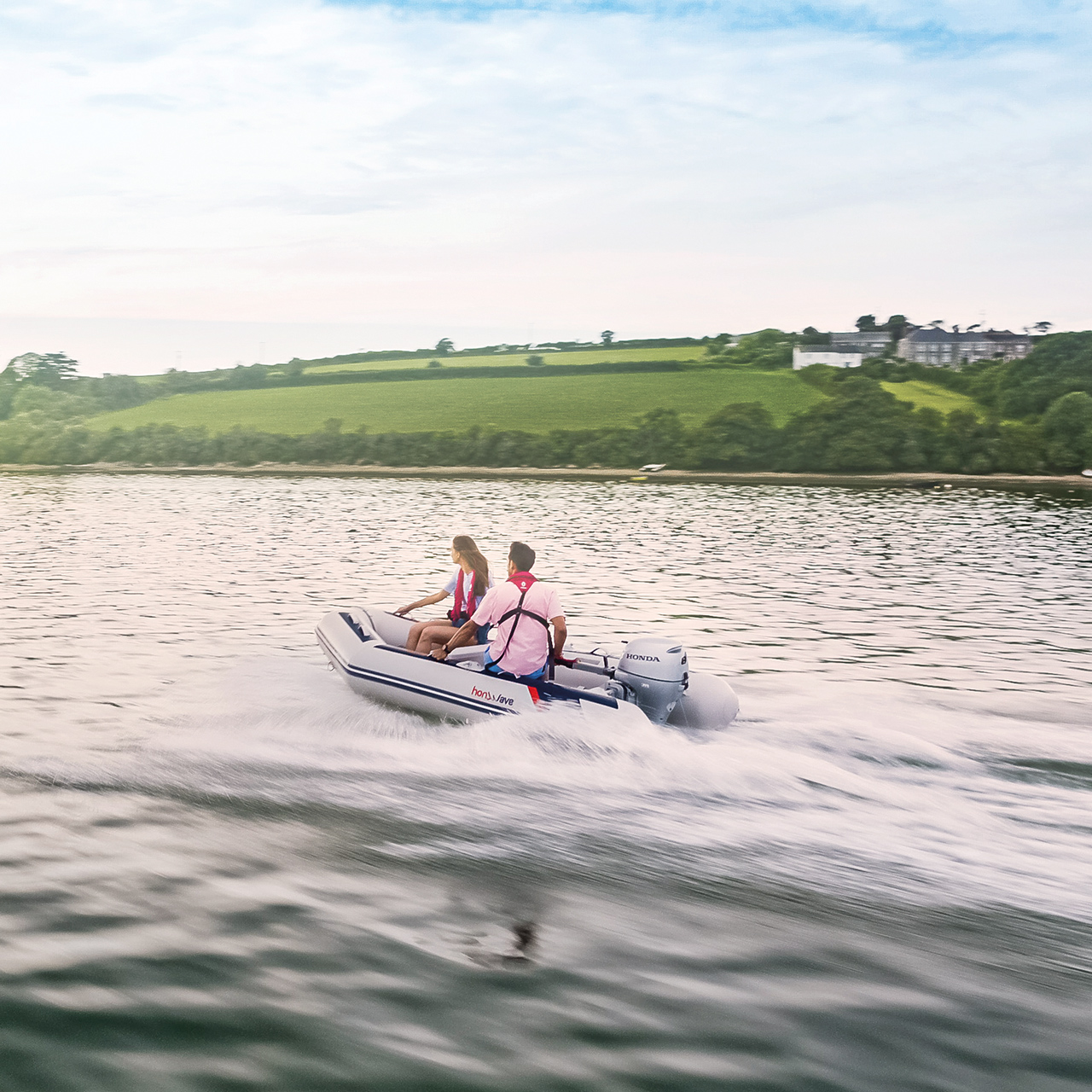 Paar auf einem Honwave-Boot mit Honda BF-Motor auf einem See. 