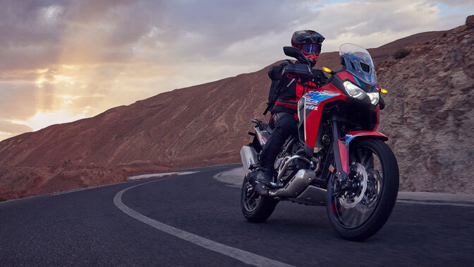 Model mit CRF1100L Africa Twin-Motorrad auf einer Bergstraße.