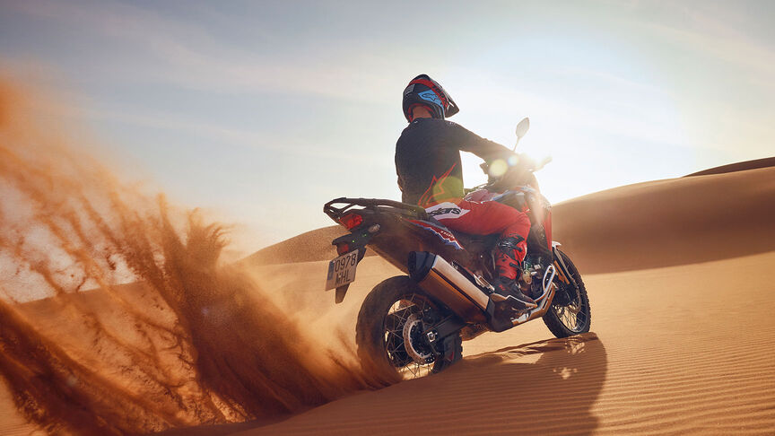 Model auf einem CRF1100L Africa Twin-Motorrad in einer Wüste.