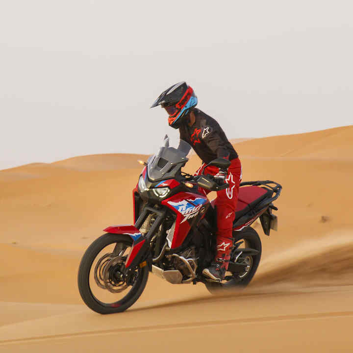 Model mit CRF1100L Africa Twin-Motorrad auf einer Wüstenstraße.