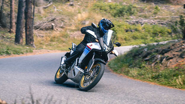 XL750 Transalp in einer Kurve auf einer Straße im Wald.