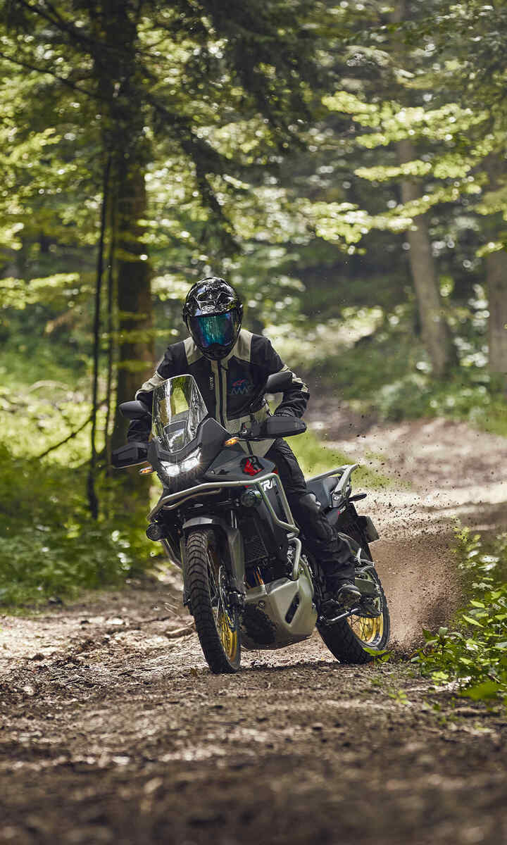 XL750 Transalp mit Model in einem Wald.