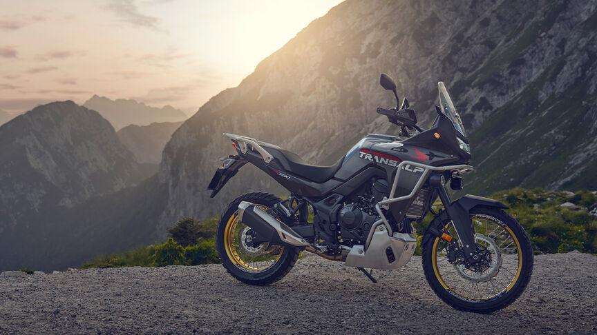 Model fährt XL750 Transalp-Motorrad in einem Waldgebiet.
