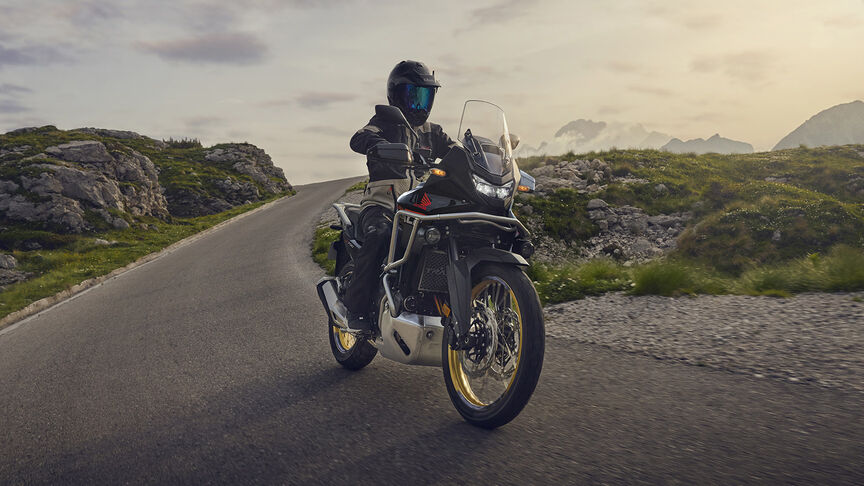 Model fährt XL750 Transalp-Motorrad in einem Waldgebiet.