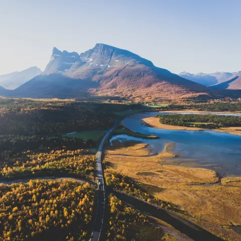 Klassische norwegisch-skandinavische Gebirgslandschaft im Sommer mit Straße, Bergen und Fjord unter blauem Himmel, Nordnorwegen, Finnmark, Drohnenaufnahme