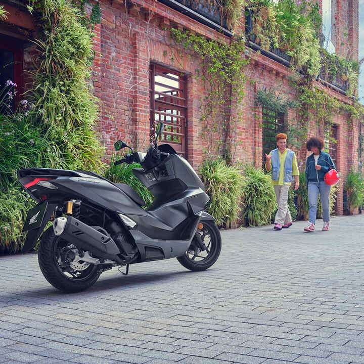 Models gehen auf den Roller PCX125 zu.