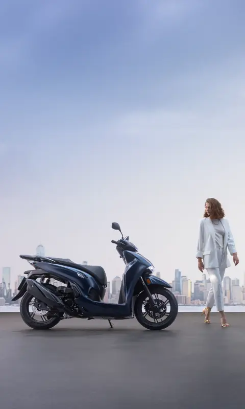 Eine Frau steht neben einem Honda SH350i in der Stadt.