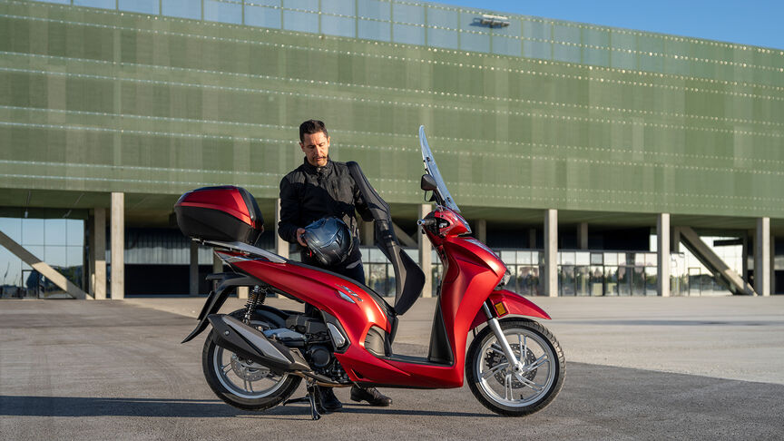 Honda SH350i in Rot, 3/4-Frontansicht rechts, mit Fahrer, Straße