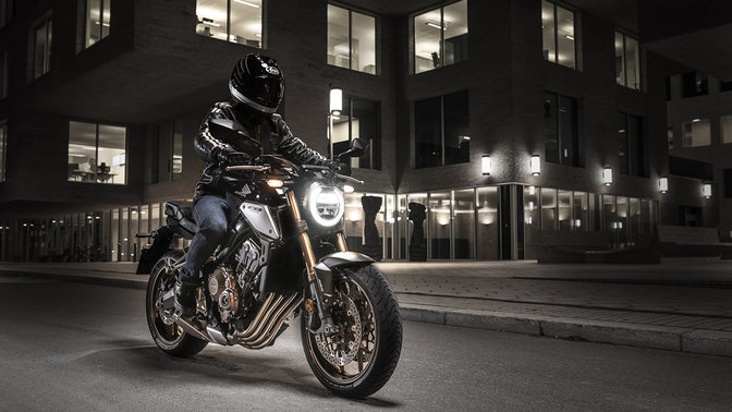 CB650R Neo Sports Café, 3/4-Frontansicht rechts, in der Stadt bei Nacht mit Fahrer