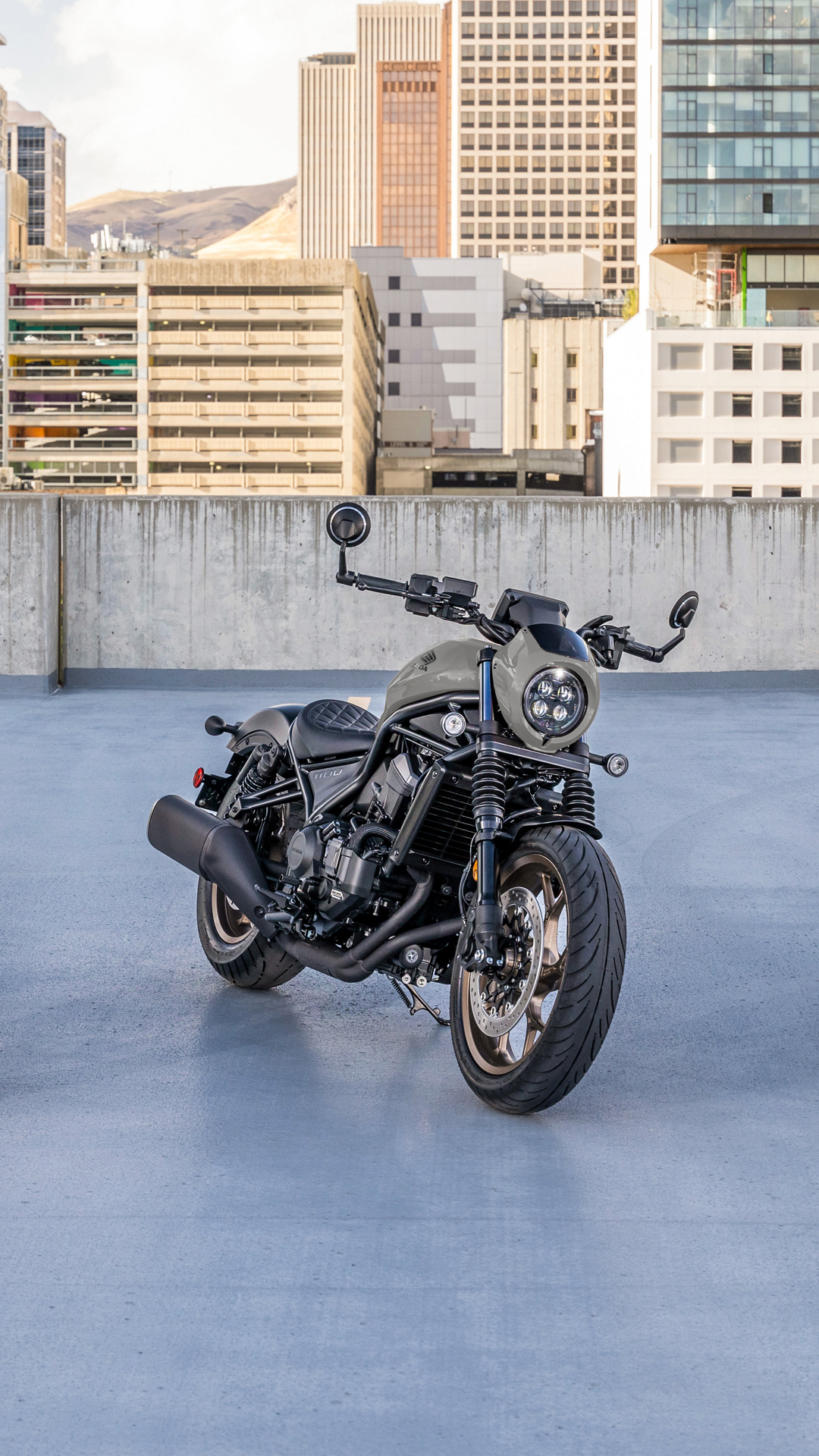 Ein CMX1100 Motorrad im Freien vor einem modernen Gebäude.