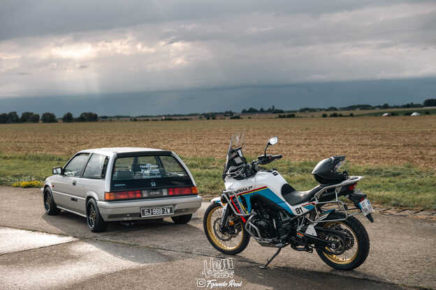 Ein alter Civic und ein Honda-Motorrad, die vor einem Feld geparkt sind.