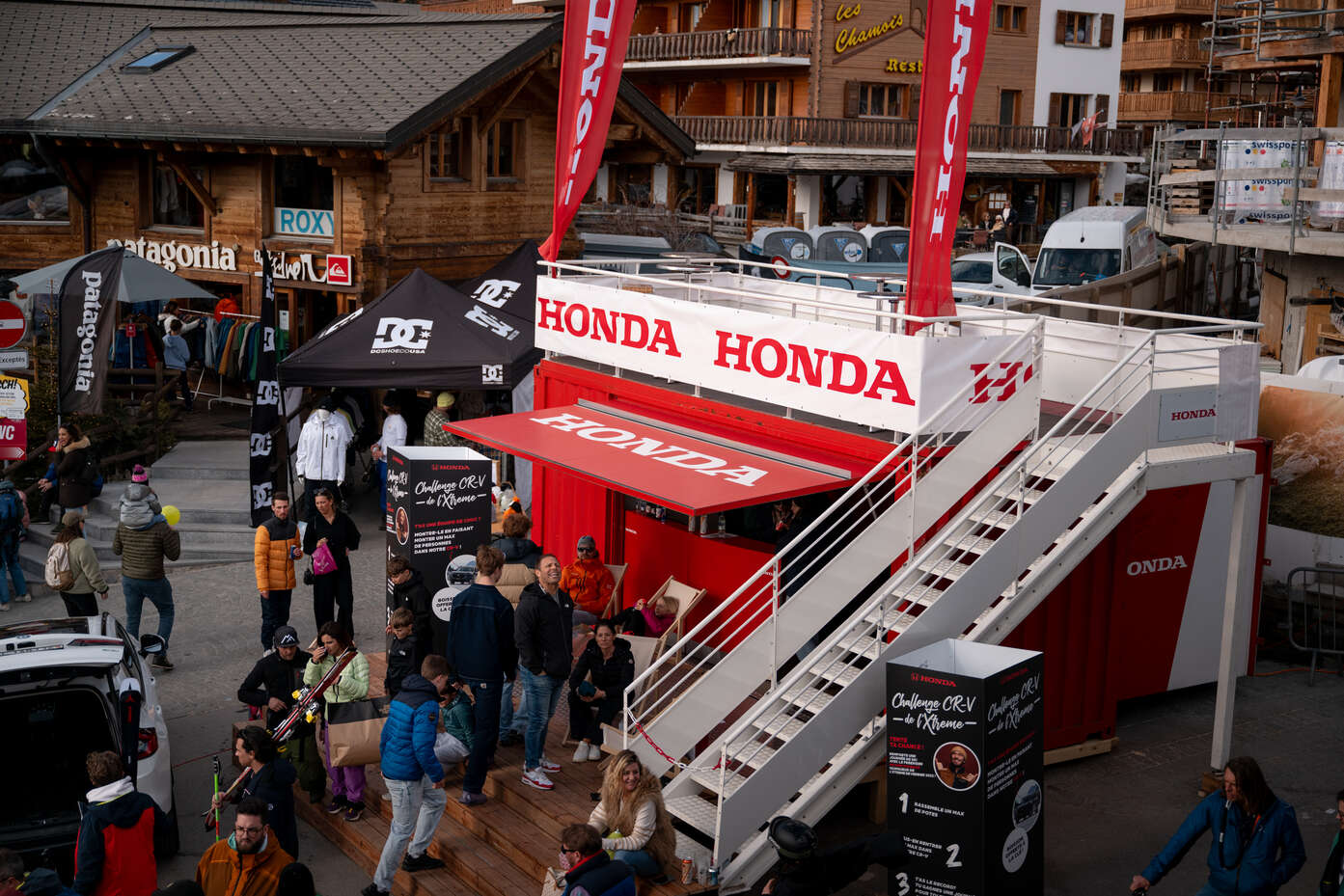 Honda-Stand in einer Gasse in Verbier mit Menschen drum herum