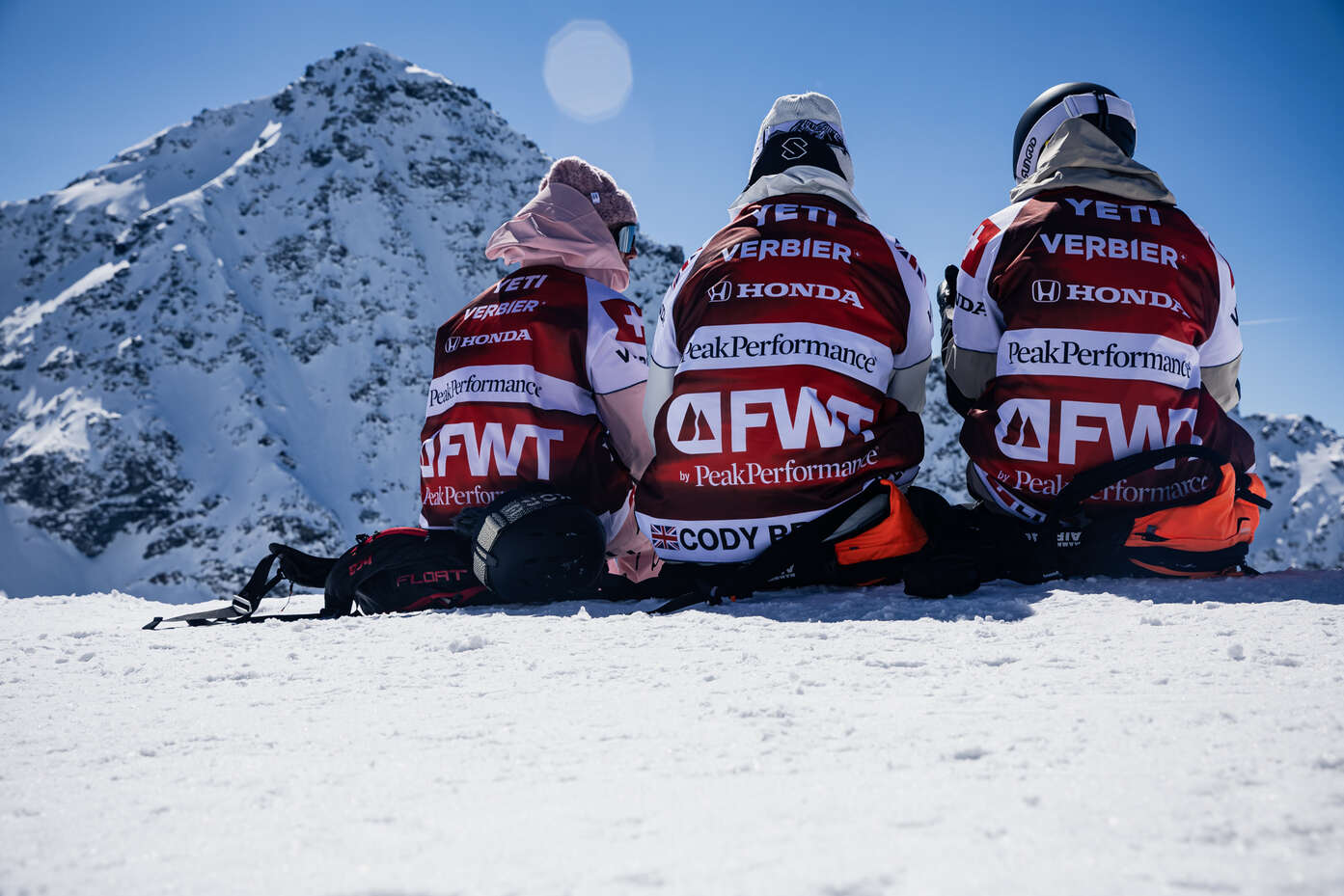 3 Athleten sitzen auf einem Berggipfel in Verbier