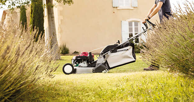 Seitenansicht: Honda HRD-Rasenmäher mit Höhenverstellung in einem Garten.